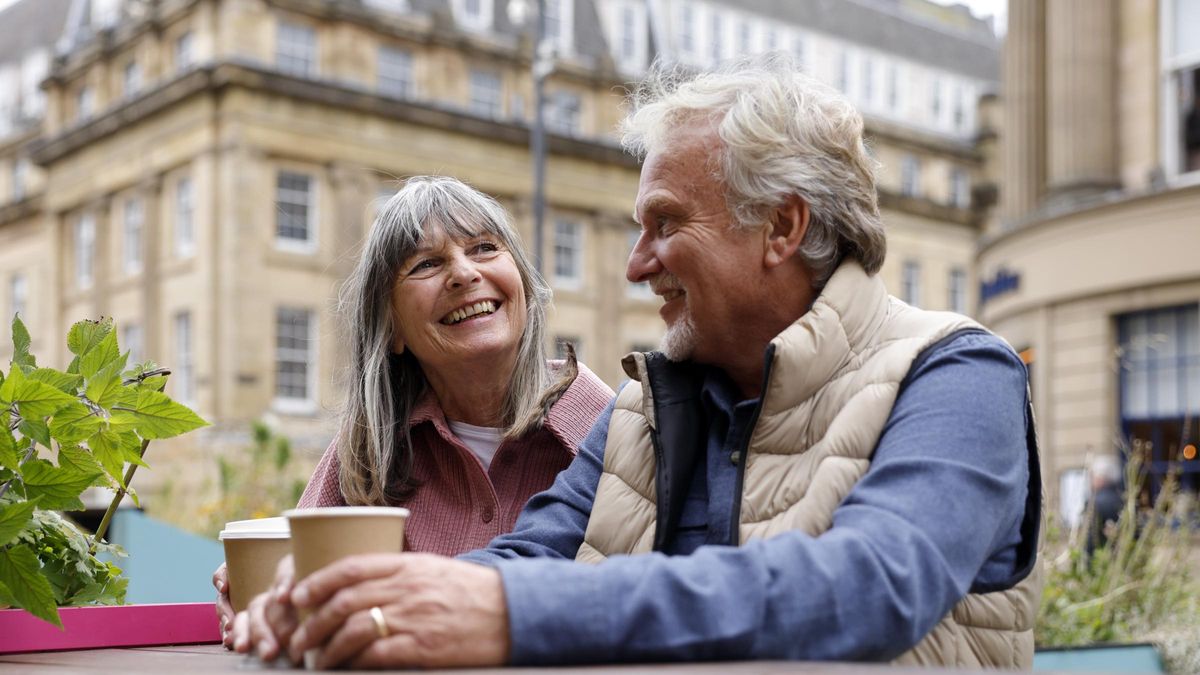 A happy senior couple enjoying a moment together seated at an outdoor city cafe.