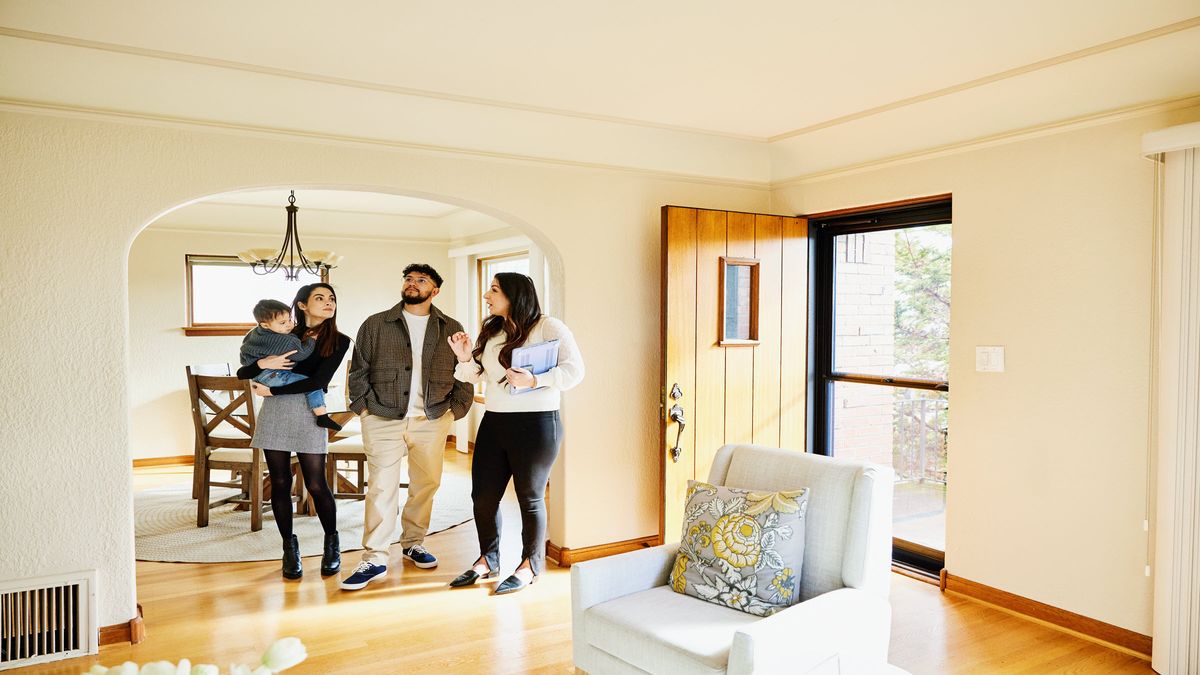 A couple, their toddler, and realtor standing in the foyer of a new home