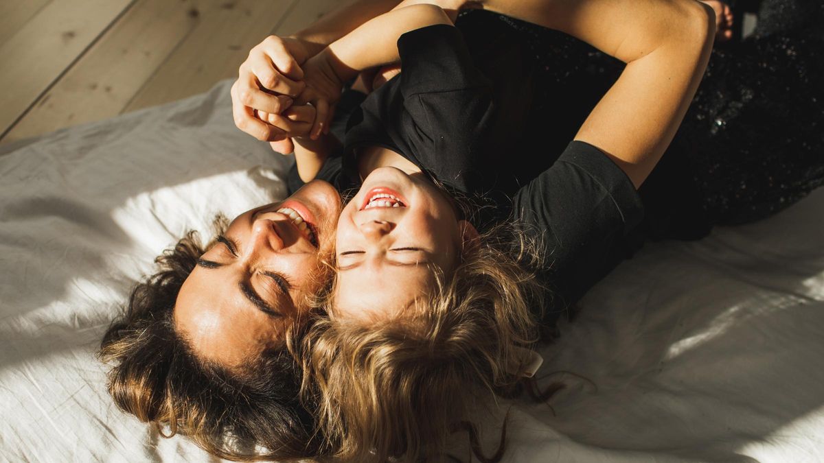 Happy mother and daughter having fun and playing together on the bed at home.