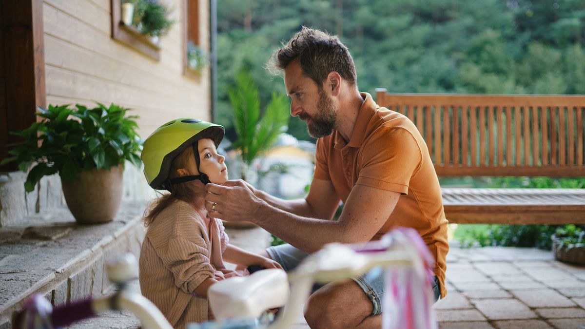 A loving dad preparing his daughter for a bike ride.