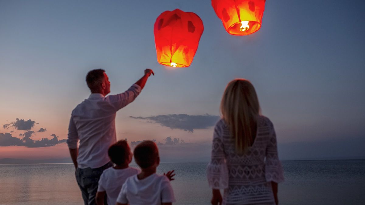 Family releasing paper lanterns by the sea
