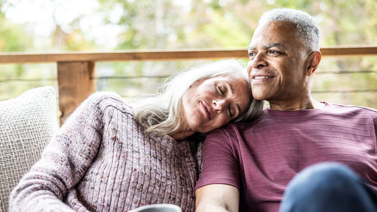 Couple having coffee and embracing on back porch of vacation home - stock photo