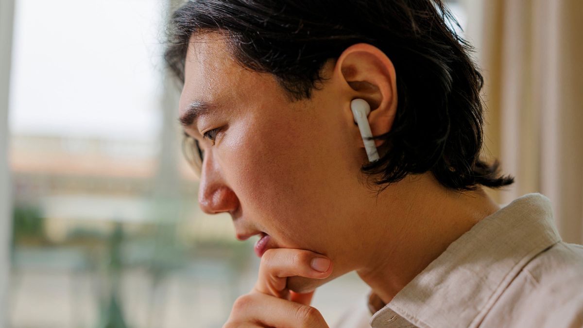 Focused office worker wearing earbuds at office, contemplating stock market moves and reading Northwestern Mutual Weekly Market commentary.