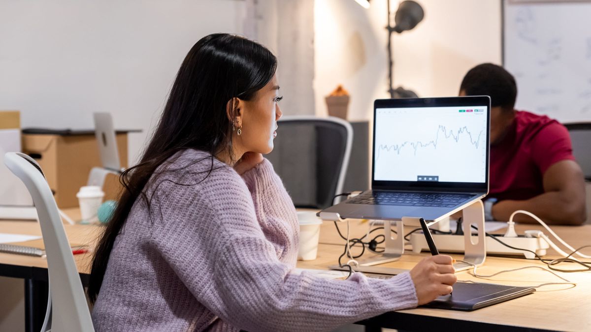 Woman tracks economic and market movements on her computer in a modern office.