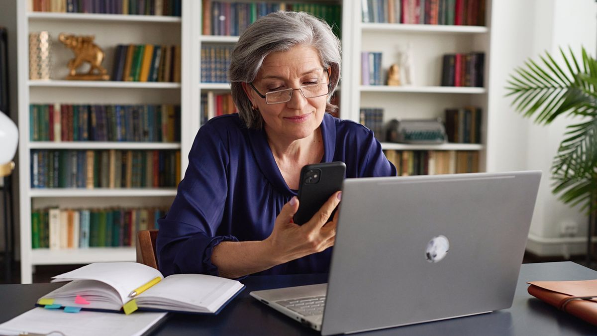 Woman contemplates financial returns on laptop in book-lined office