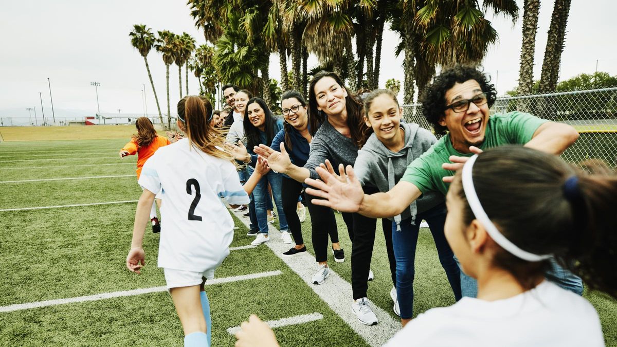 Young female soccer players high fiving parents on sidelines after soccer game