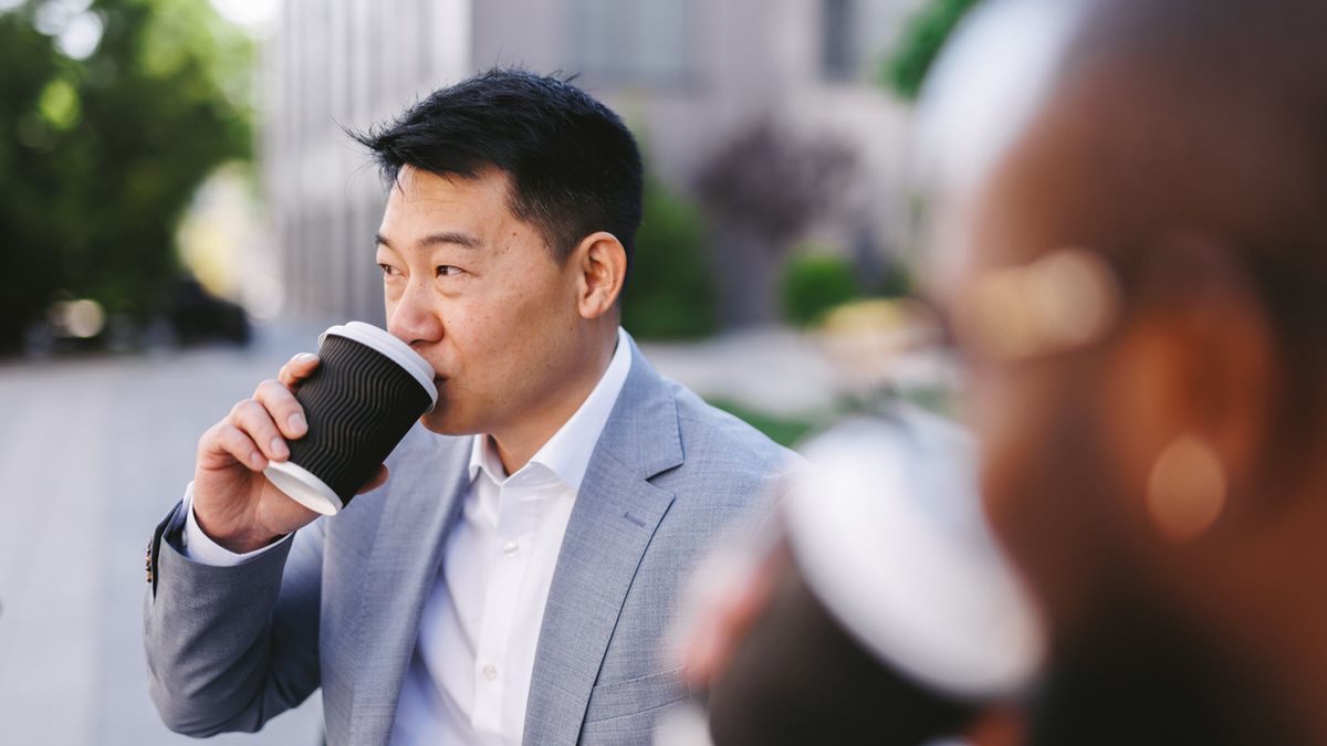 usinessman enjoys coffee in a sunlit courtyard outside modern office