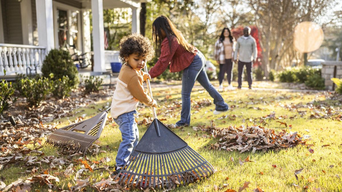 Children raking leaves in front yard of home
