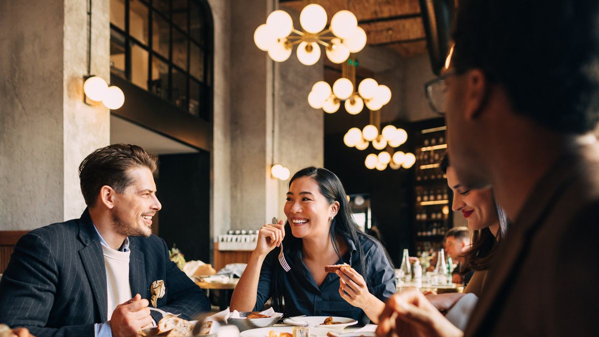 Colleagues enjoy business lunch and discuss markets