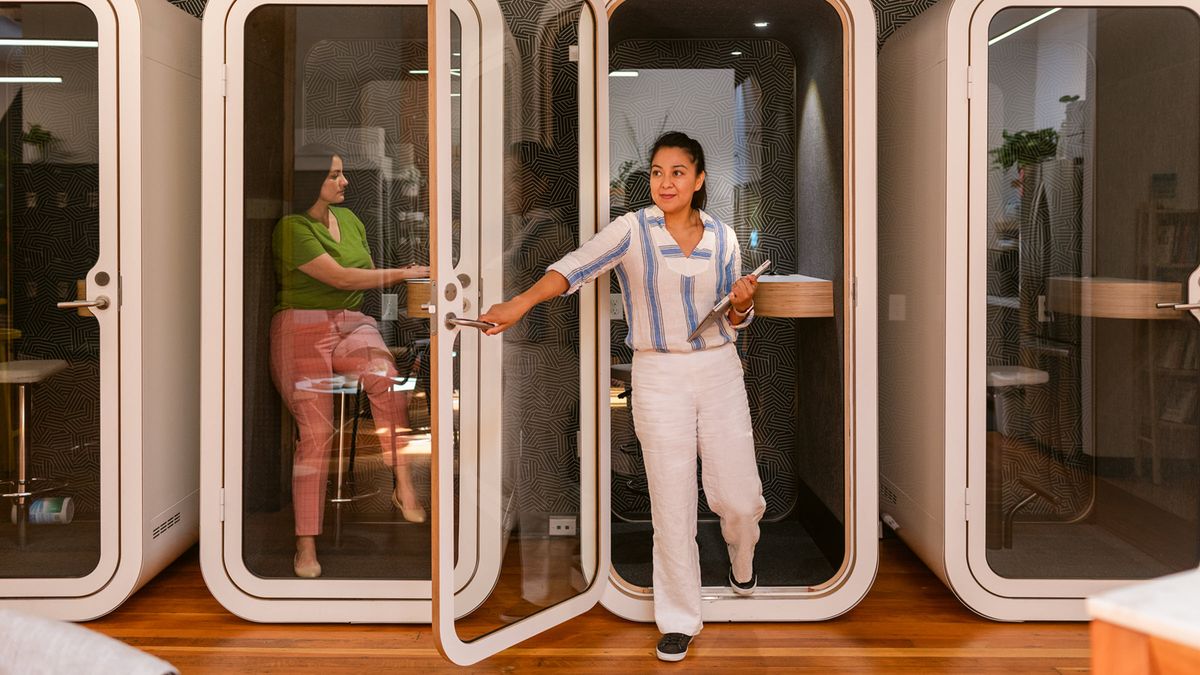 Co-workers use private booths in modern office