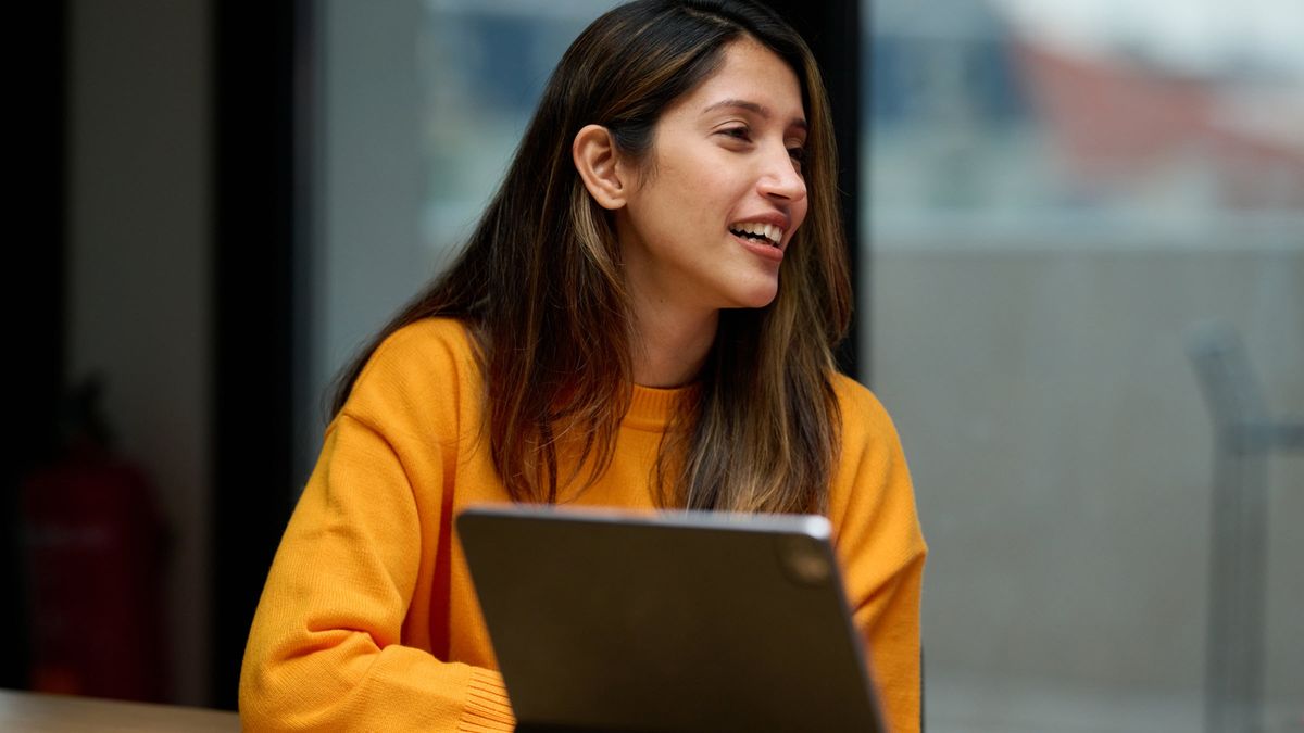 Smiling woman researches economy and markets on tablet in modern office