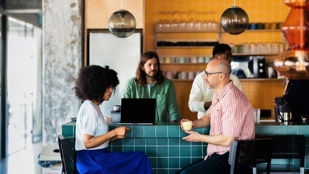 Co-workers Chatting Over Coffee at Modern Cafe Counter 