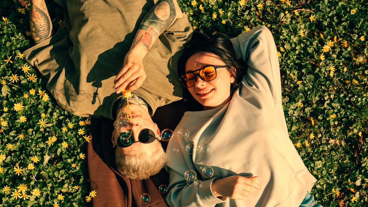 Young couple lying on grass blowing soap bubbles 