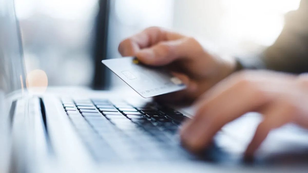 Man holding credit card while using a computer