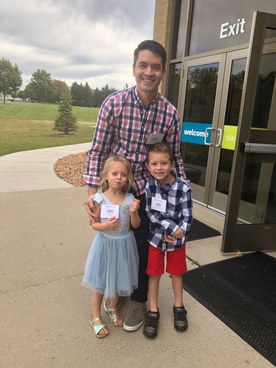Photo of Brian and his two kids greeting at church