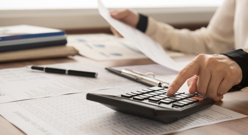 finger clicking buttons on a calculator to determine financial plan