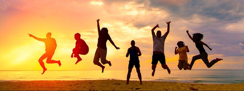 Family jumping on a beach at sunset.