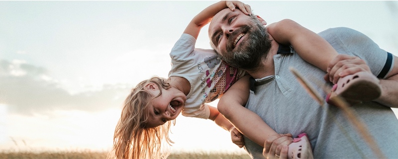 Daughter laughing on father's shoulders