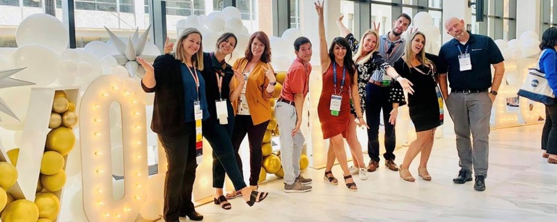 Image shows a group of people standing in a row at an event making fun poses. 