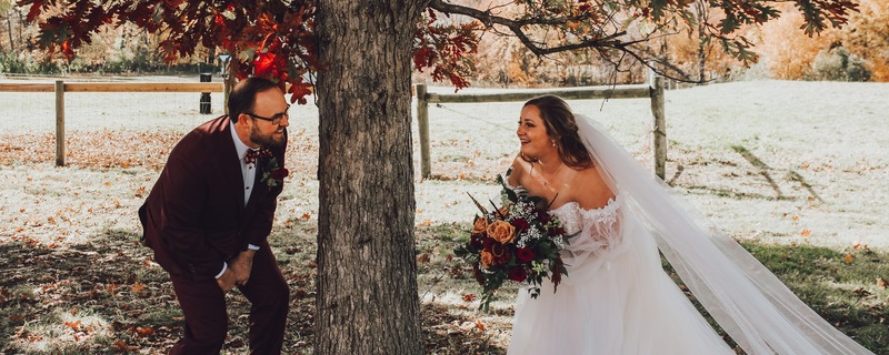 Justin & wife, Kara smiling around tree at Wedding